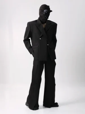 Oversized black double-breasted suit and wide-leg flared trousers set shown from a three-quarter front view with structured shoulders, matte suiting fabric, and ankle side slits