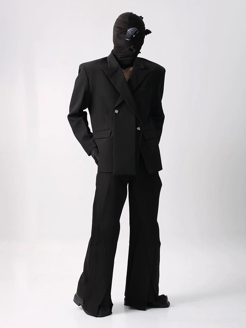 Oversized black double-breasted suit and wide-leg flared trousers set shown from a three-quarter front view with structured shoulders, matte suiting fabric, and ankle side slits