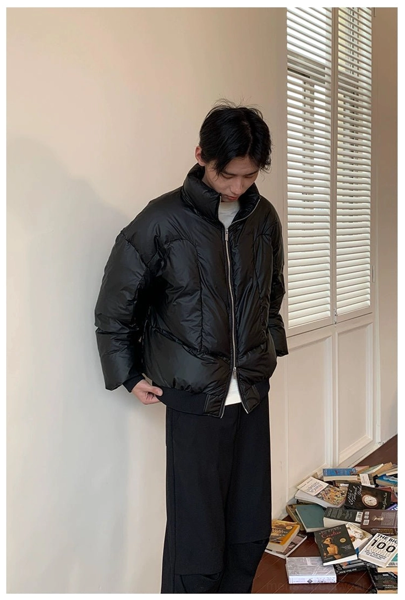 Black glossy duck down puffer jacket with high stand collar worn in a minimalist indoor streetwear setting