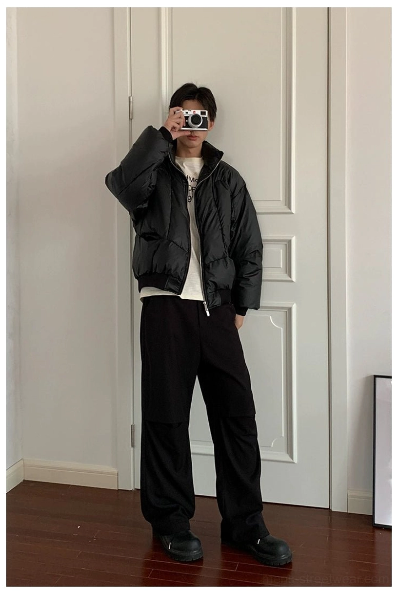 Male model wearing oversized black duck down puffer jacket with stand collar and cargo pants in casual streetwear look