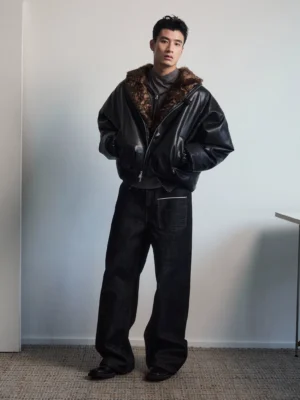Full-body front view of an oversized black faux leather blouson jacket with brown faux fur collar and padded winter streetwear silhouette