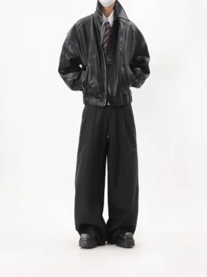Black oversized faux leather zip-up bomber jacket front full-body view styled with striped tie dress shirt and wide-leg black pants
