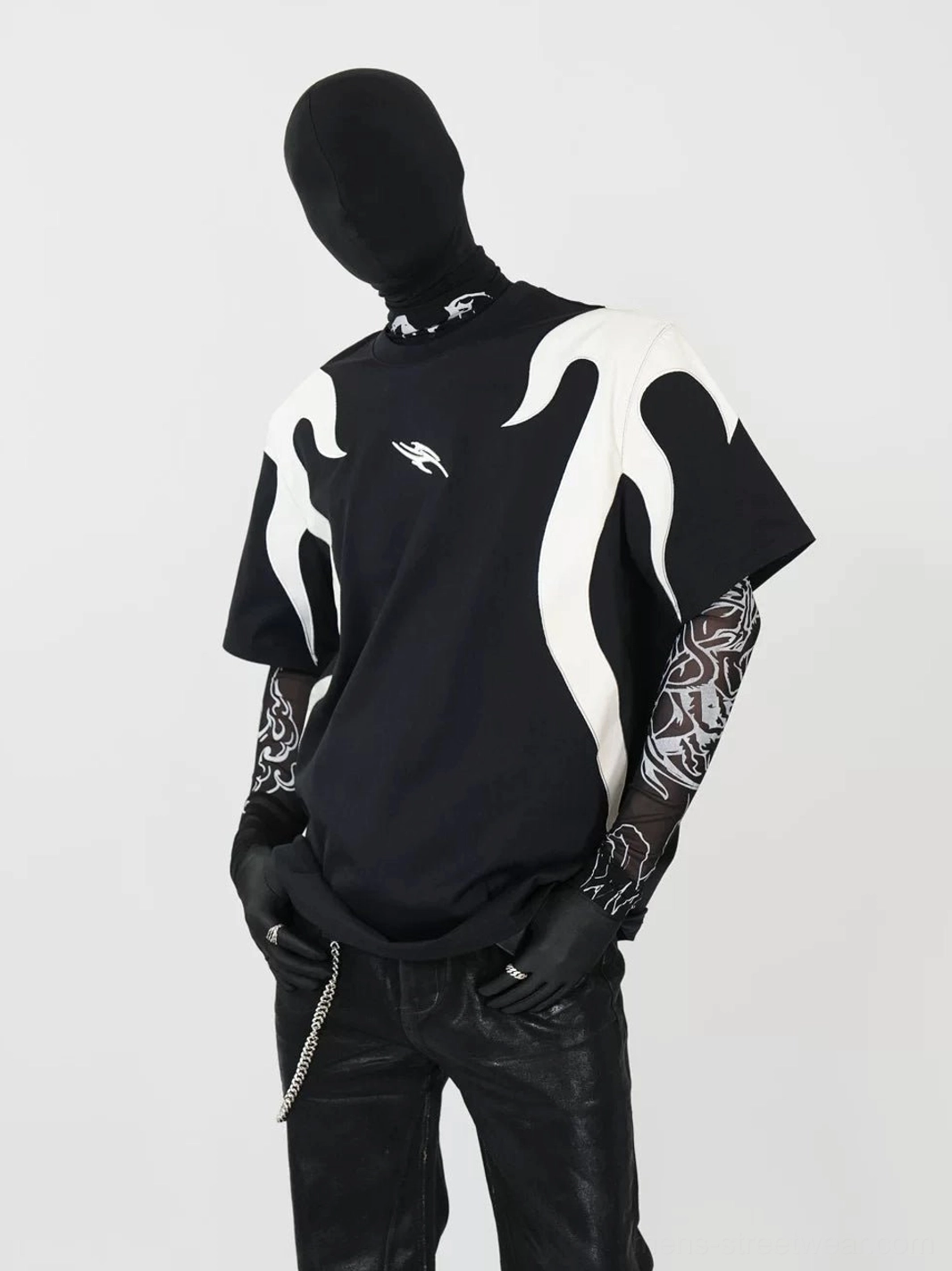 Left three-quarter front view of an oversized black flame panel T-shirt with off-white flame appliques, drop shoulders, tattoo mesh sleeves, black gloves, leather pants, and cyberpunk streetwear styling
