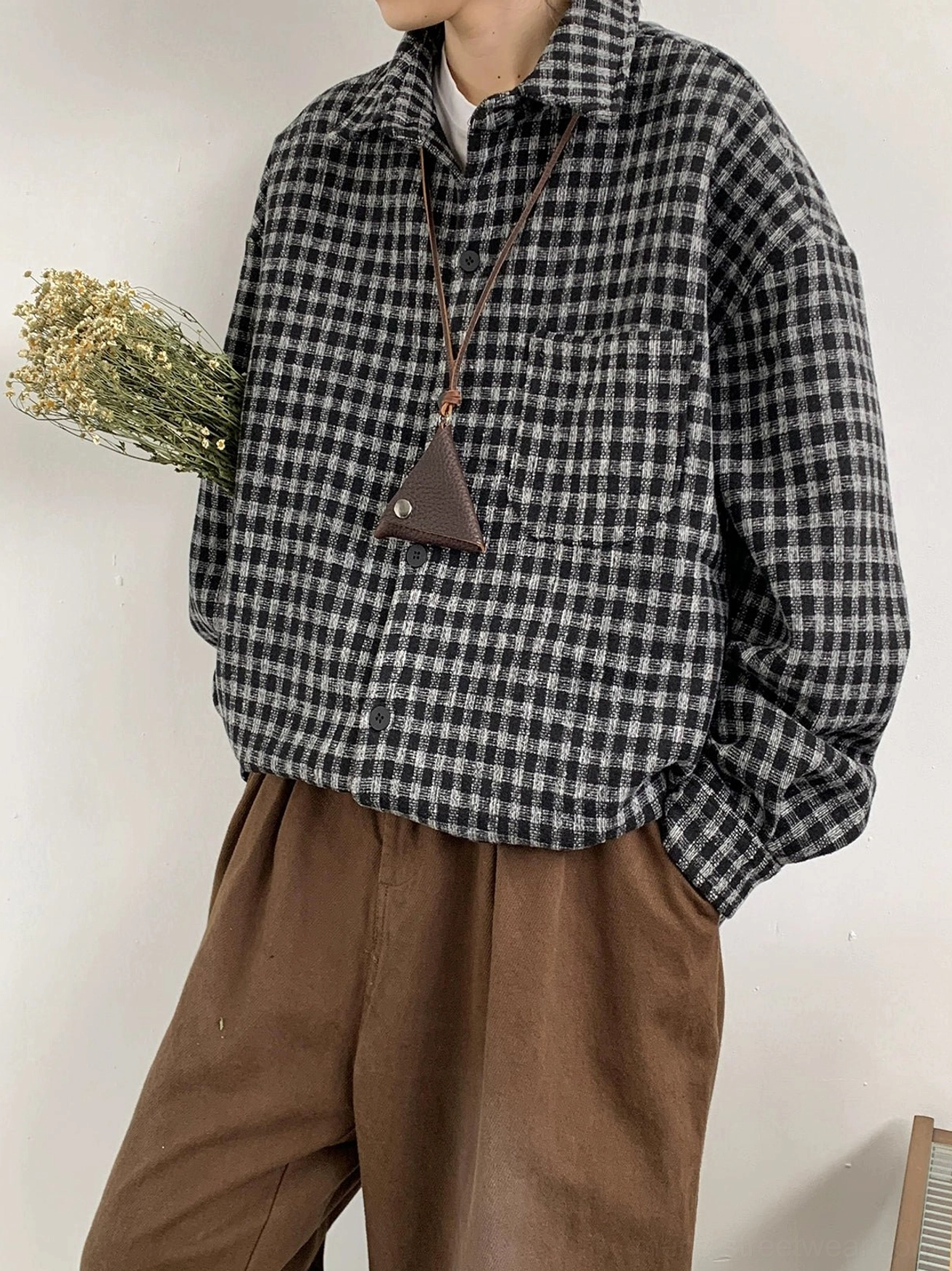 Low-angle full-body view of an oversized black and gray plaid flannel shirt with loose fit chest pocket and streetwear accessories