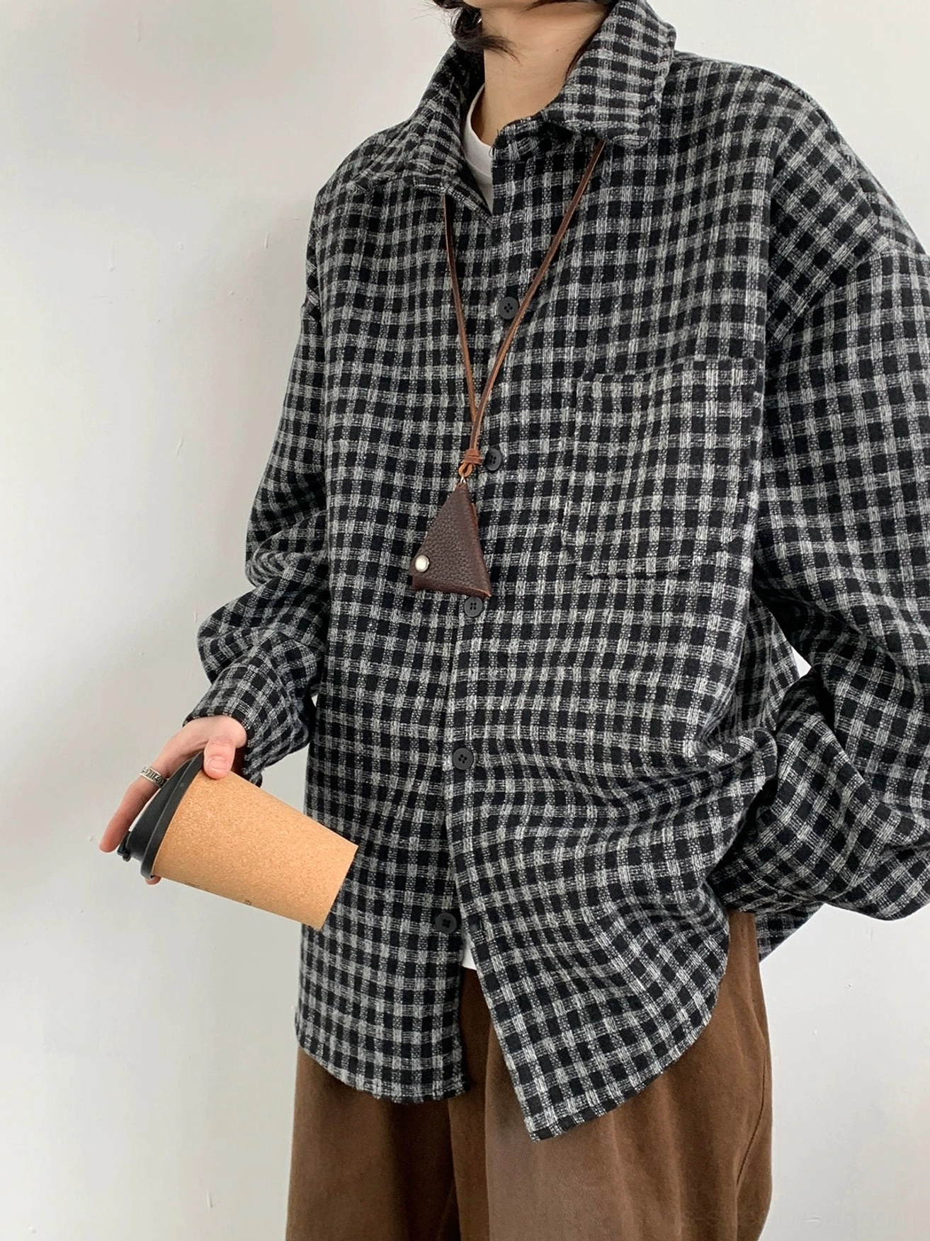 Three-quarter view of black and gray oversized plaid flannel shirt with button closure curved hem and relaxed Korean streetwear styling