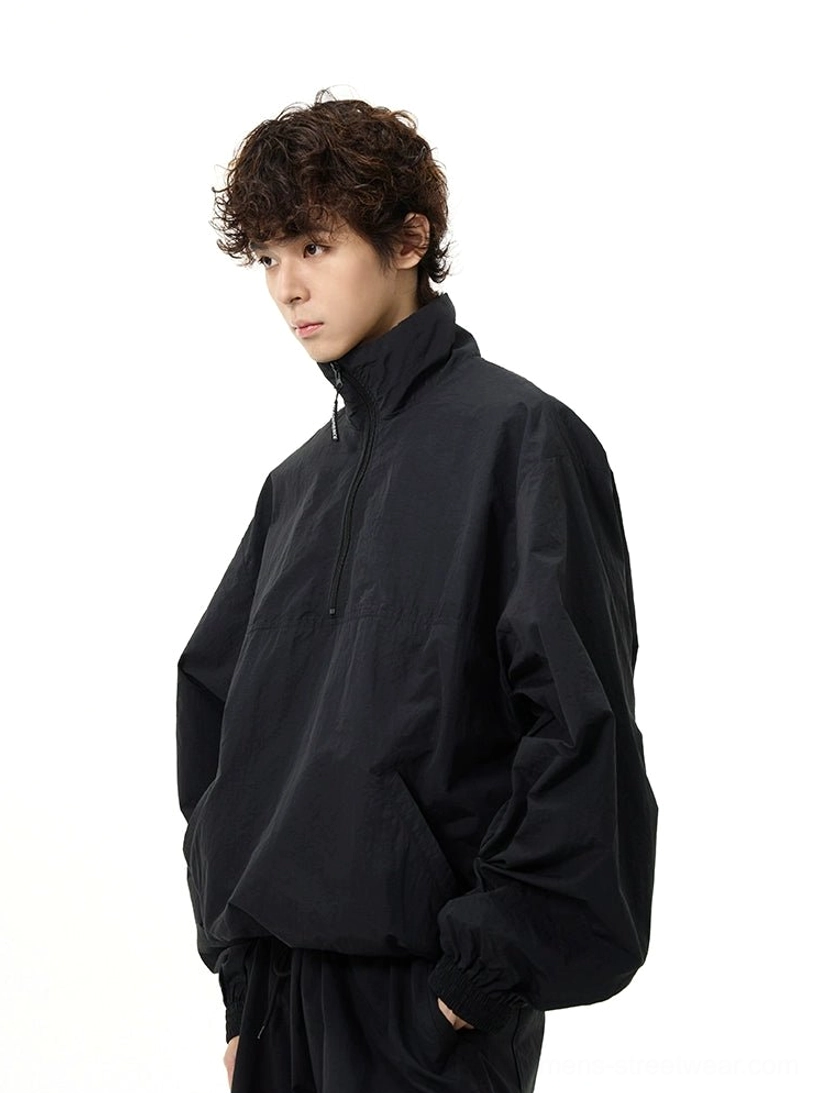 Three-quarter side view of an oversized black half-zip windbreaker with dropped shoulders and relaxed Korean streetwear styling