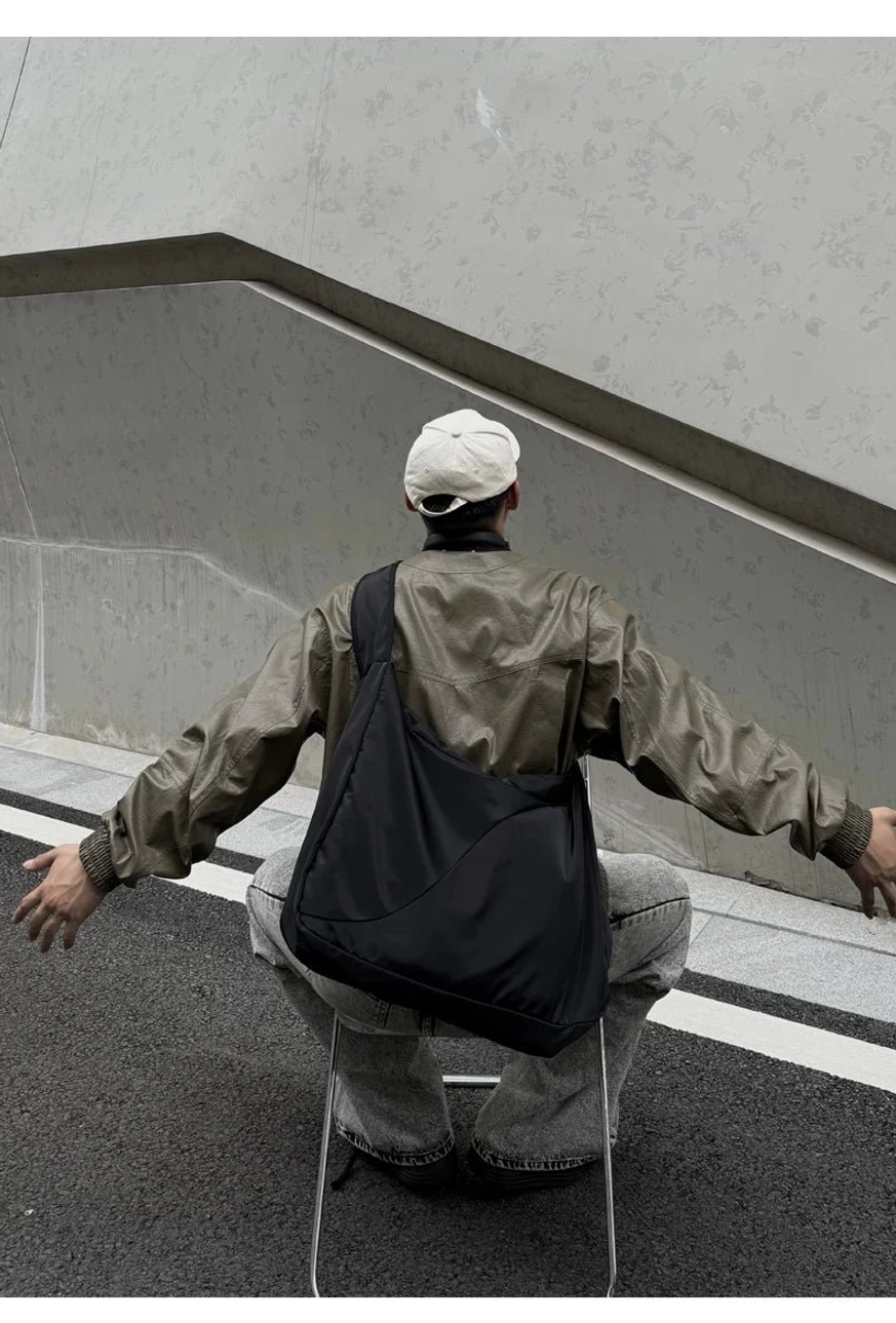 Large black nylon hobo sling bag positioned at the lower back with industrial Korean streetwear styling
