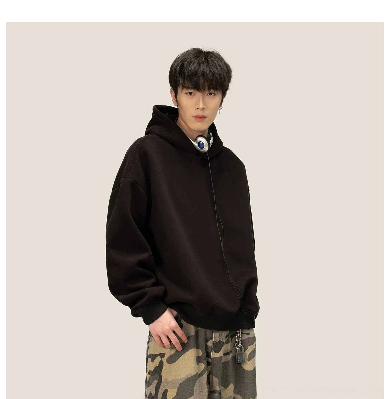 Three-quarter view of oversized black pullover fleece hoodie with hidden drawstring hood and clean streetwear finish