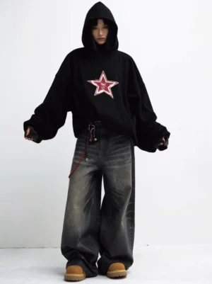 Female model styling oversized black red star graphic hoodie with washed baggy jeans and work boots front view