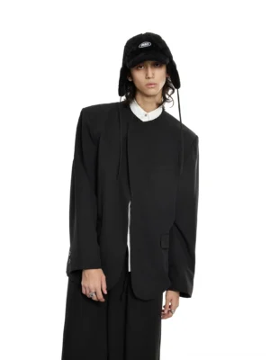 Front view of oversized black structured collarless blazer with padded shoulders and flap pockets