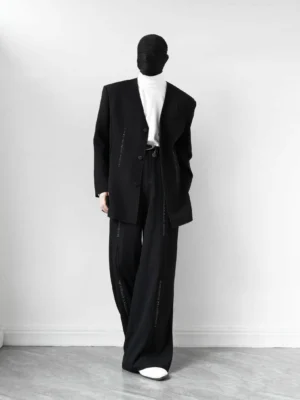 Side view of oversized black lapel-free V-neck blazer styled with a white turtleneck in a minimalist studio