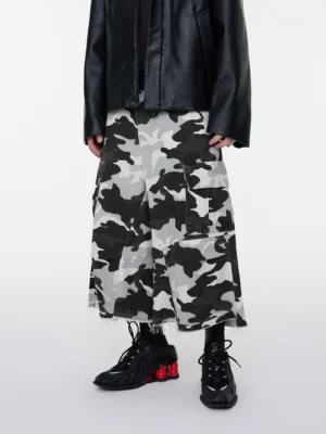 Front view of oversized black and white snow camouflage cargo shorts with wide cropped legs, side flap pockets, and a raw frayed hem