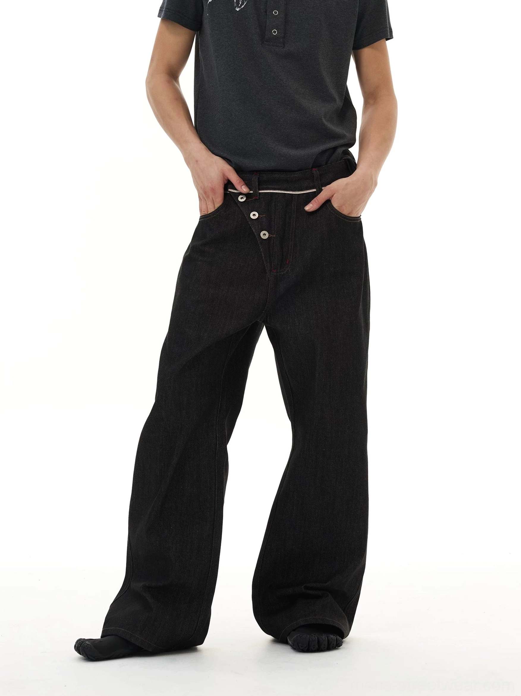 Three-quarter front view of oversized black wide-leg jeans featuring contrast waistband trim and asymmetric front buttons
