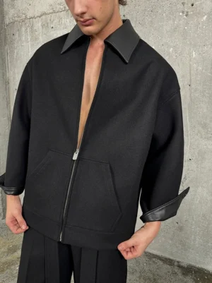 Close-up front view of oversized black wool blend streetwear jacket with faux leather collar cuffs front zipper and patch pockets