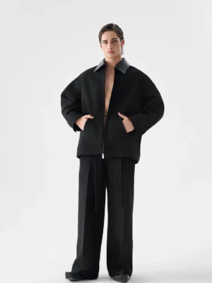 Full front outfit view of oversized black faux leather trim jacket styled with black wide leg trousers in Seoul streetwear style