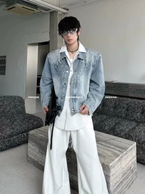 Front full-body view of a men's vintage blue oversized chevron denim jacket with structured shoulders, faded wash, white wide-leg pants, black platform loafers, and crossbody bag
