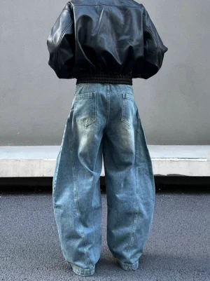 Back view of oversized vintage blue orbital panel jeans showing classic denim back pockets, wide-leg balloon silhouette, soft stacked hem, and cropped black leather jacket