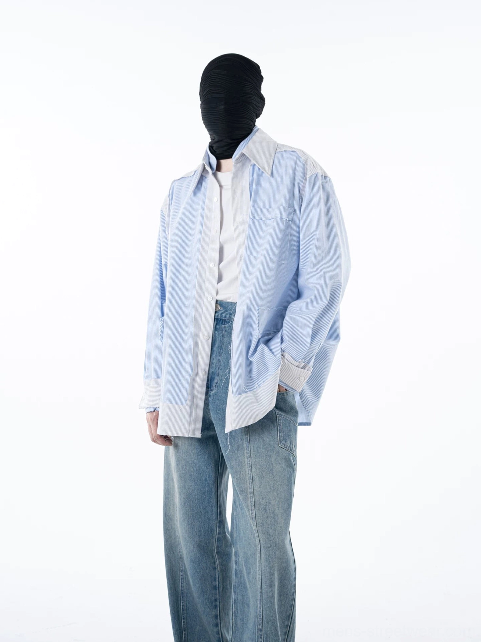 Side view of an oversized blue pinstripe button-up overshirt with white placket and hem worn over a white tee and jeans
