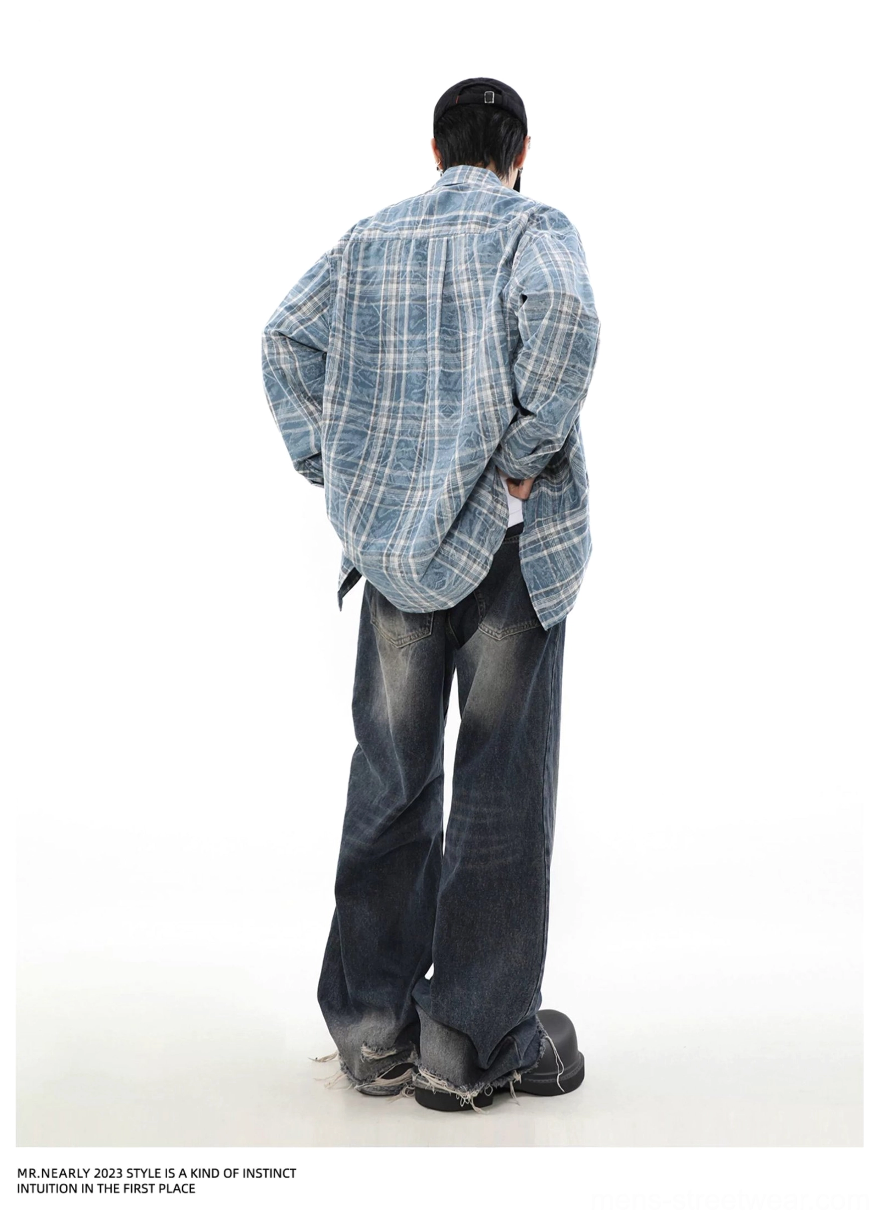 Back view of an oversized blue plaid overshirt showing the relaxed silhouette and slightly longer rear hem with wide-leg jeans