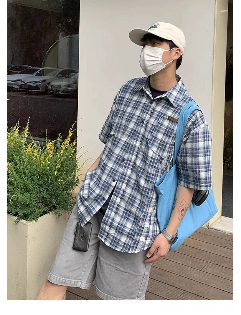 Front three quarter view of blue white plaid oversized shirt with button closure chest pocket and extended hem
