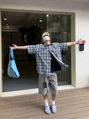 Oversized blue and white plaid Korean streetwear shirt styled with grey shorts and light blue sneakers front view