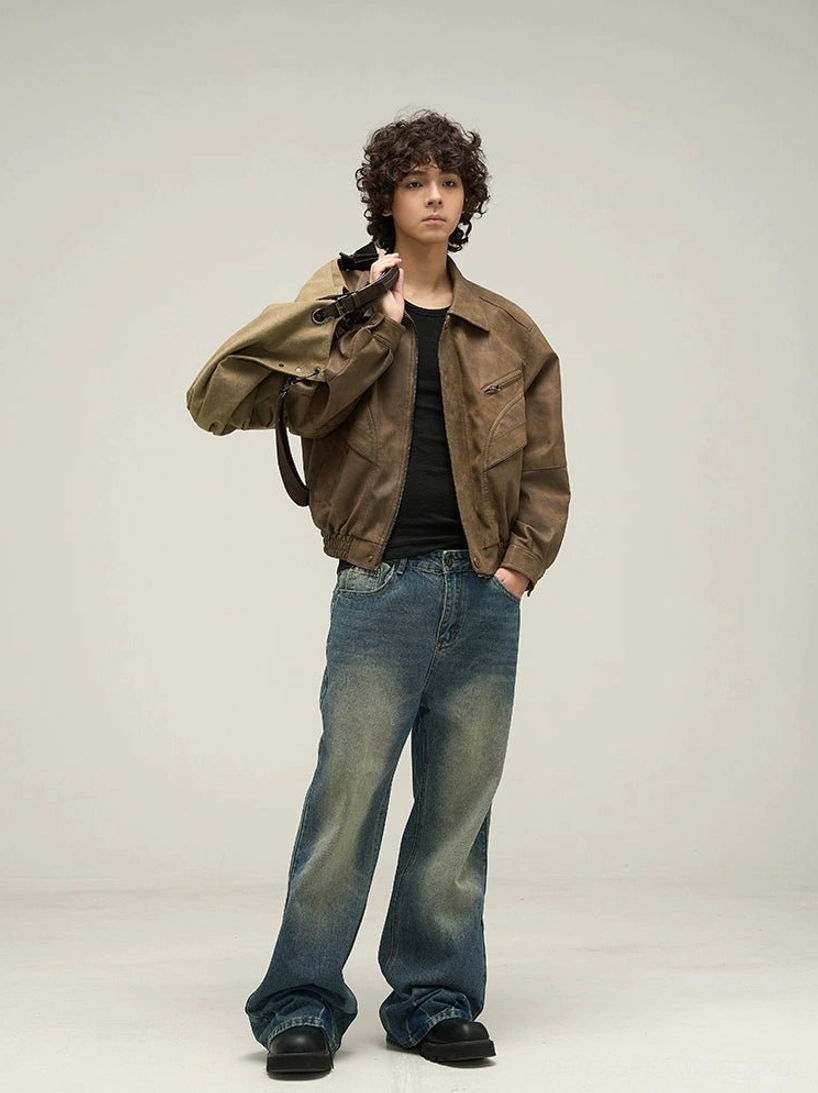 Side view of an oversized vintage brown faux leather jacket with relaxed fit, ribbed hem, blue jeans, and canvas shoulder bag