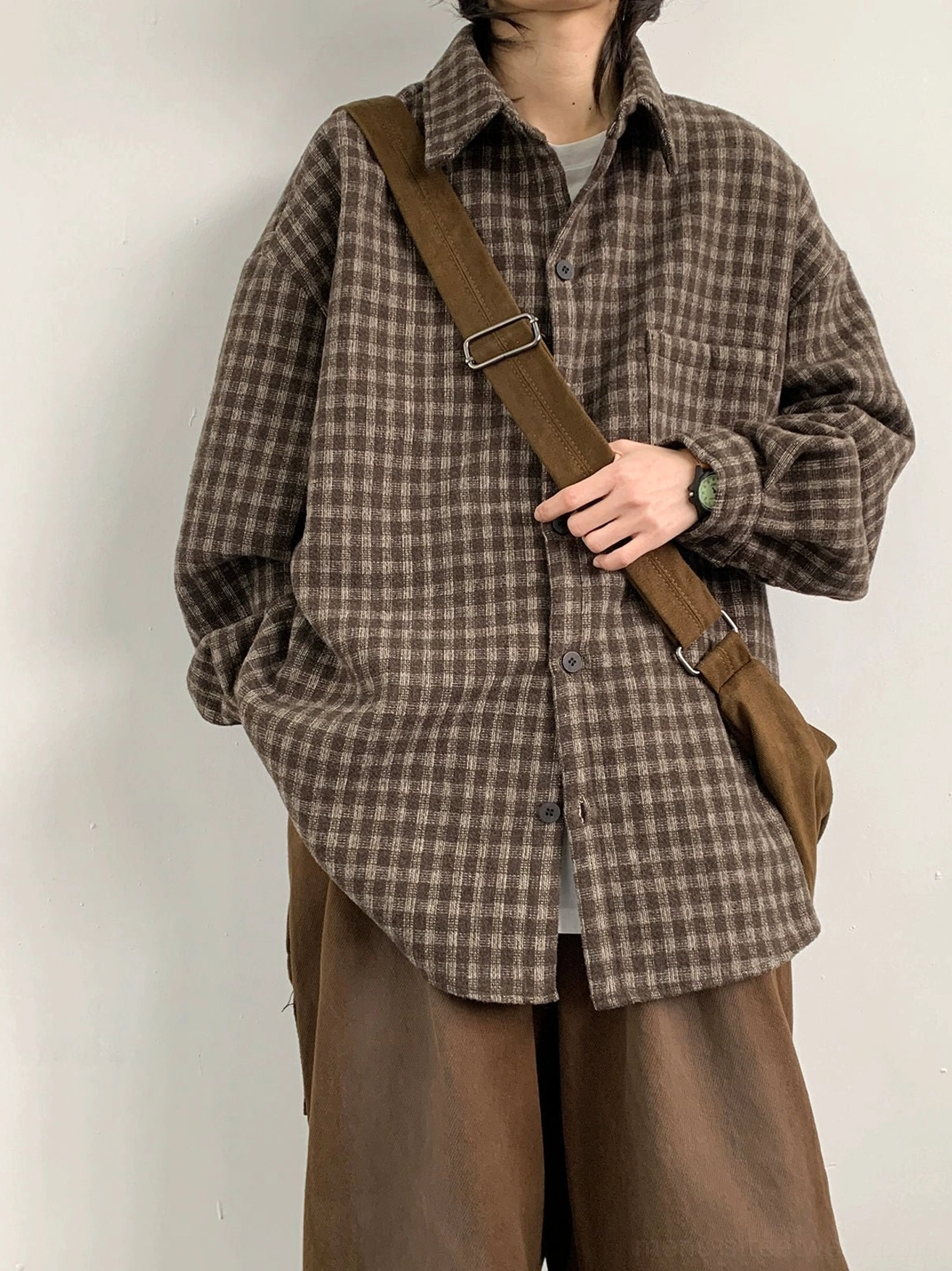 Front full-body view of an oversized brown plaid flannel shirt with drop shoulders chest pocket curved hem and wide-leg streetwear styling