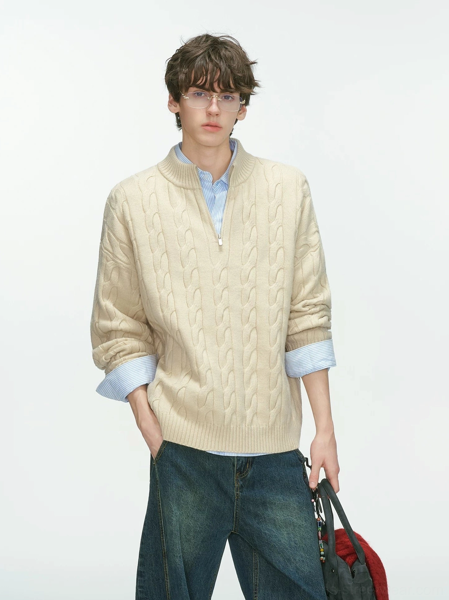 Beige oversized cable-knit half-zip sweater styled with a light blue shirt, dark wide-leg jeans and a black red tote bag