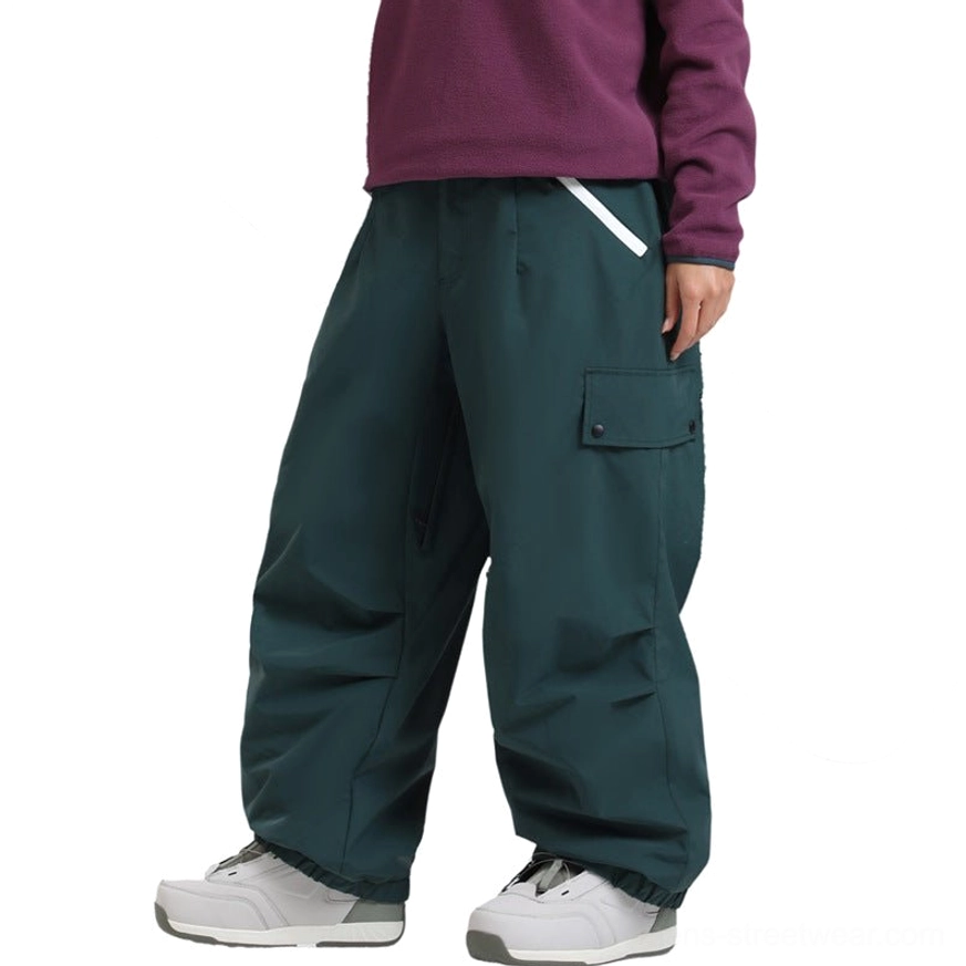 Oversized cargo snow pants with waterproof shell, wide-leg snowboard silhouette, utility pocket design, snow gaiters, and contemporary Korean outdoor streetwear styling