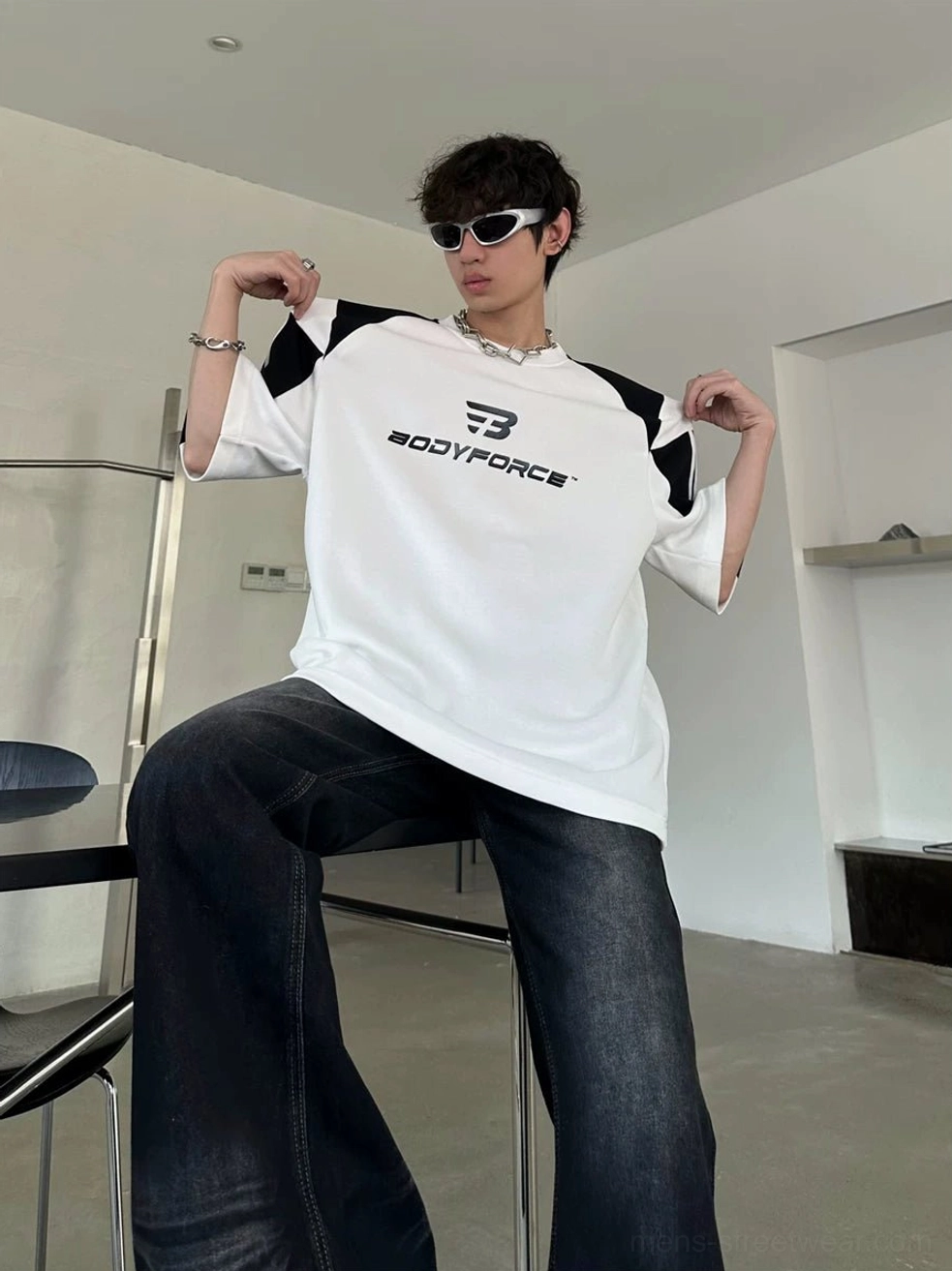 Oversized colorblock streetwear tee with varsity sleeve stripes styled in a casual seated outfit