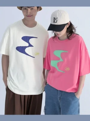 Two models wearing oversized contrast patch logo tees in neon pink and off-white with abstract wave chest graphics and relaxed drop shoulder streetwear styling