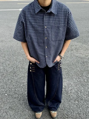 Oversized dark blue plaid short sleeve shirt worn with black T shirt and wide leg decorative jeans in Seoul streetwear style