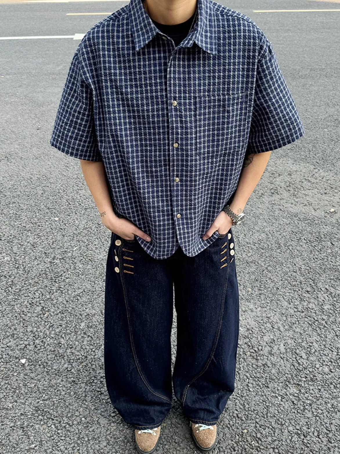 Oversized dark blue plaid short sleeve shirt worn with black T shirt and wide leg decorative jeans in Seoul streetwear style