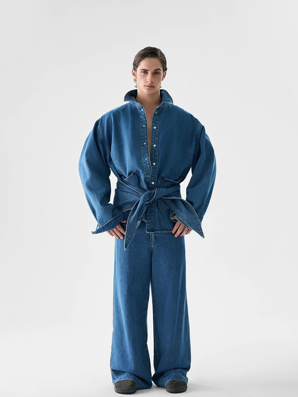 Front view of an oversized denim jacket tied at the waist with matching wide-leg indigo denim pants