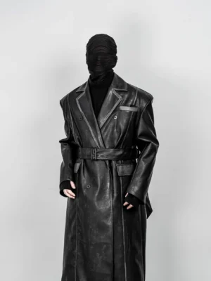 Front full body view of oversized distressed black faux leather belted trench coat with double breasted closure and wide lapels