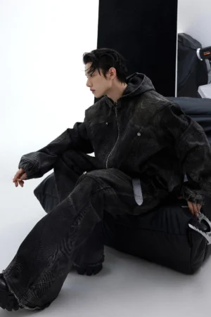 Three-quarter view of a distressed black hooded denim jacket with oversized fit, attached hood, deconstructed seams, and modern Korean streetwear silhouette