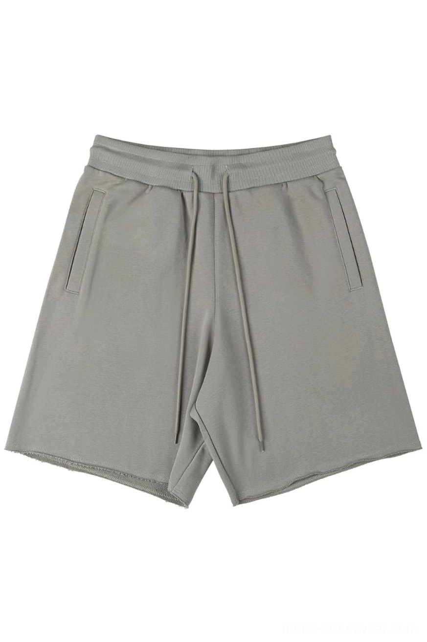 Oversized drawstring sweat shorts flat lay front view taupe grey neutral streetwear casual shorts with side pockets and raw cut hems