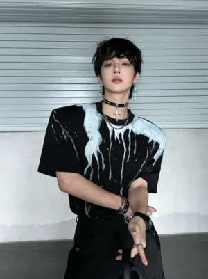 Black oversized drip print T-shirt with white dripping chest graphic shown in a parking lot streetwear outfit