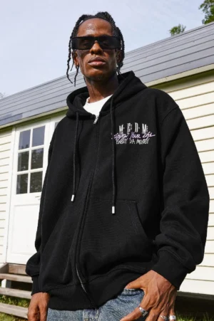Black oversized Enjoy Your Life graphic zip-up hoodie shown from the front on a male model with graffiti chest prints, drawstring hood, full zipper, and kangaroo pocket