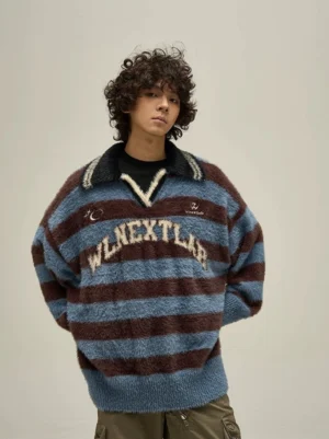 Front close-up of an oversized fuzzy striped rugby polo sweater with blue and brown horizontal stripes, contrast black collar, V-neck placket, and embroidered chest lettering