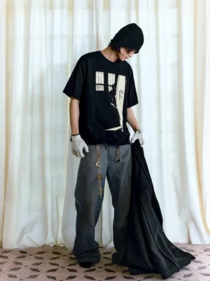 Side view of an oversized gothic streetwear graphic T-shirt showing the relaxed drop-shoulder fit, loose sleeves, and illustrated front artwork