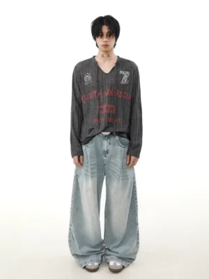 Full-body view of oversized grunge streetwear knit long sleeve top with distressed vintage prints, wide-leg jeans, and silver sneakers