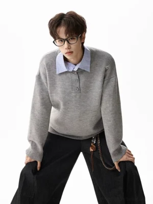 Heather gray oversized henley knit sweater layered over a blue dress shirt with cross shoulder embroidery and baggy black trousers