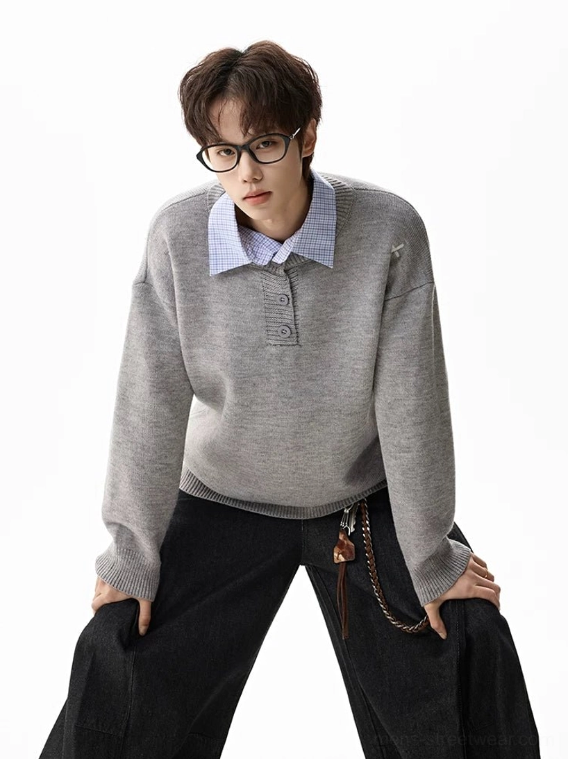 Heather gray oversized henley knit sweater layered over a blue dress shirt with cross shoulder embroidery and baggy black trousers
