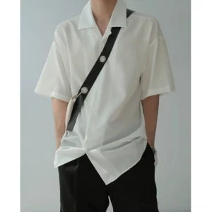 White oversized ice silk camp collar streetwear shirt front view styled with black crossbody bag and tailored shorts