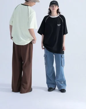 Back view of oversized Korean streetwear raglan T-shirt showing relaxed silhouette, contrast shoulder piping, and curved loose hem