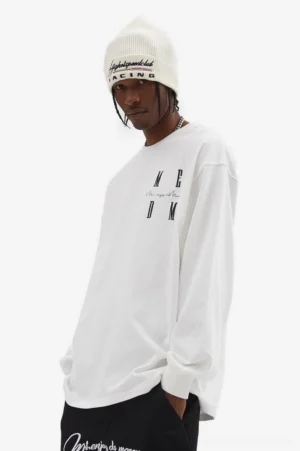 White oversized MCDM graphic long sleeve T-shirt styled with black trousers and a white knit beanie in Korean streetwear fashion