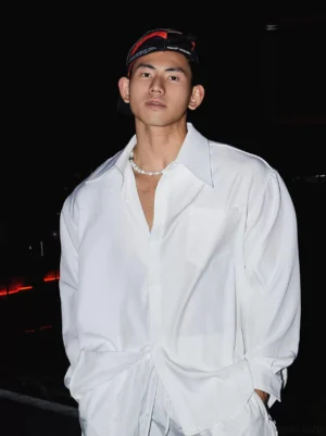 White oversized men's streetwear dress shirt with pointed collar chest patch pocket and relaxed fit styled on a model at night