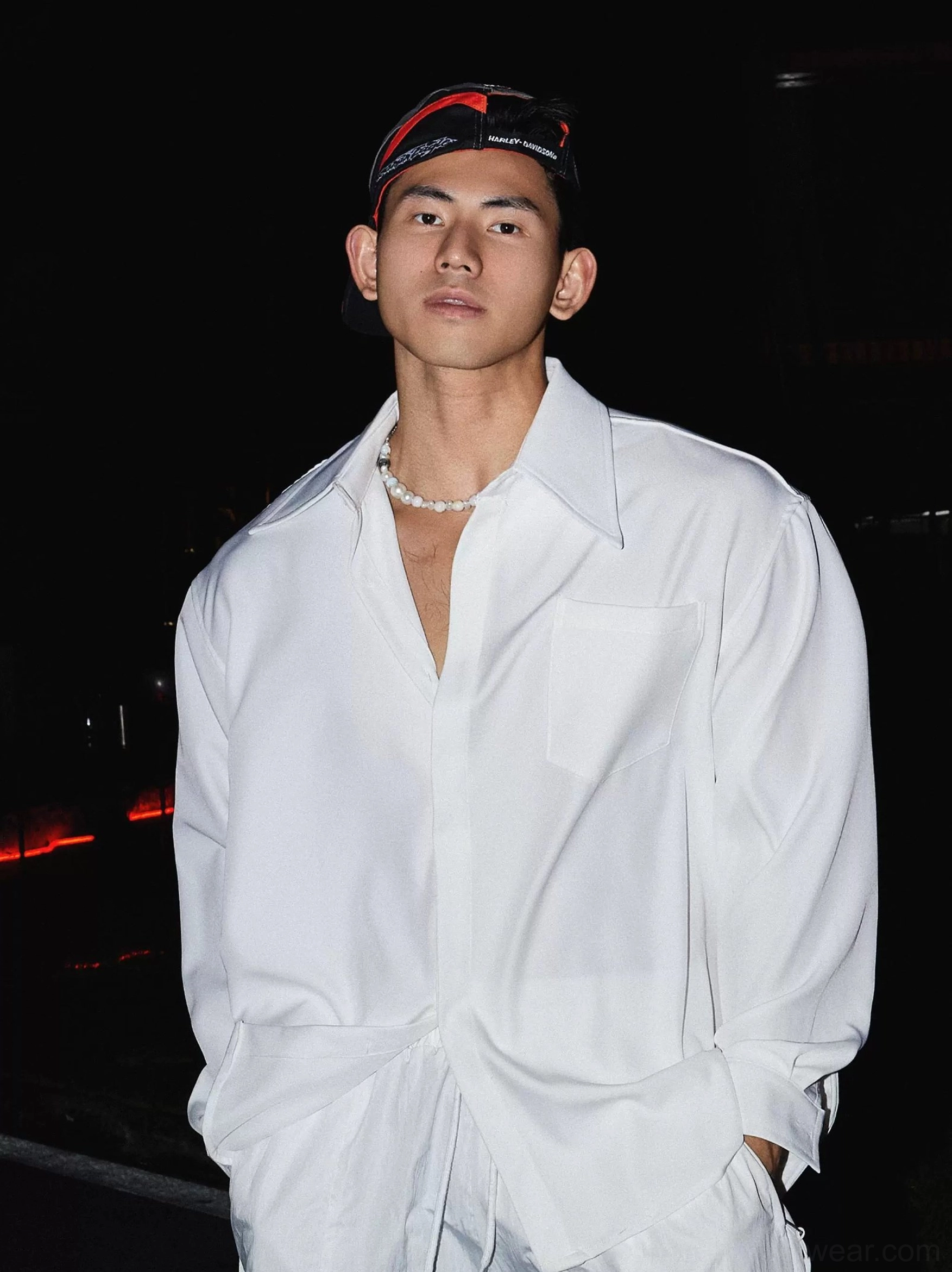 White oversized men's streetwear dress shirt with pointed collar chest patch pocket and relaxed fit styled on a model at night