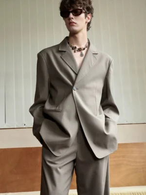 Close-up of men's oversized casual blazer showing smooth suiting fabric, dropped shoulders, notch lapel and large flap pockets